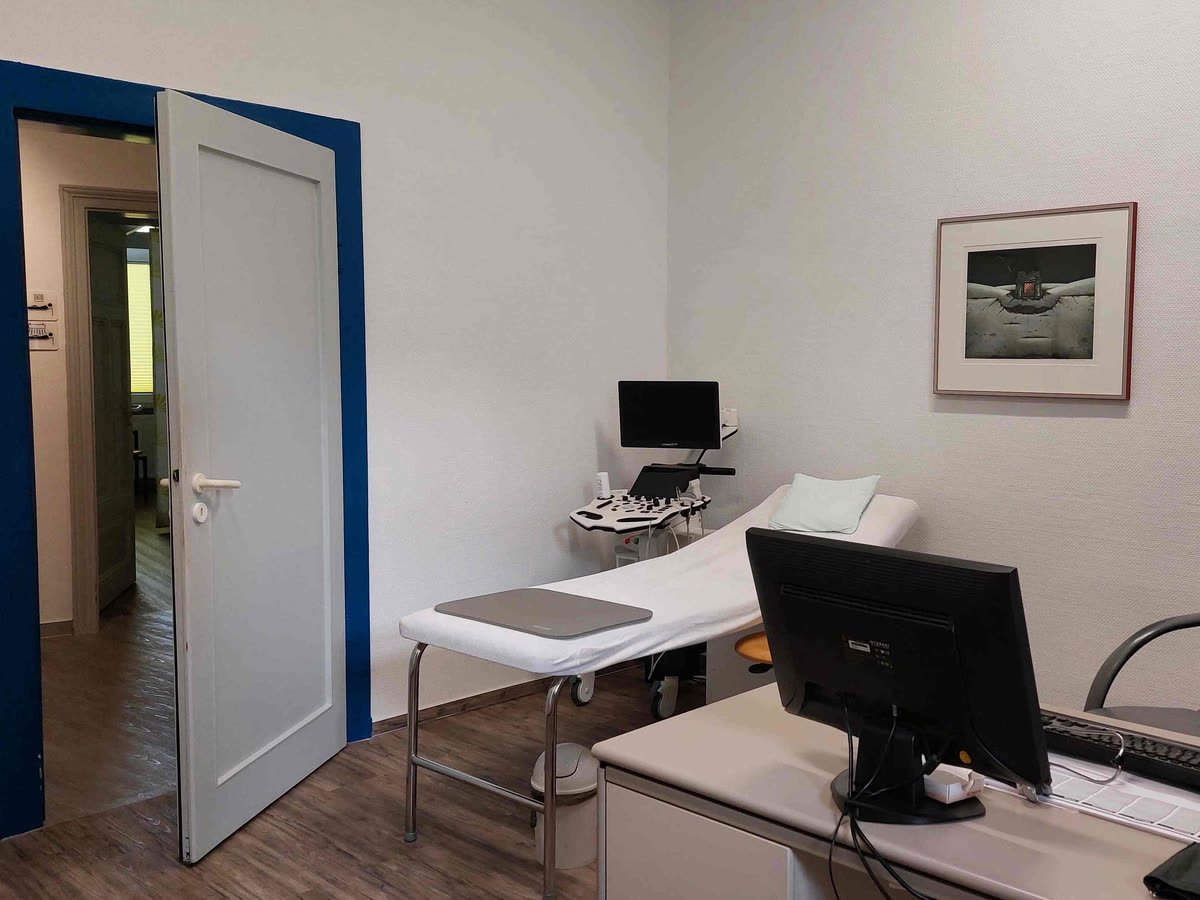 Sprechzimmer mit Untersuchungsliege, Schreibtisch und Ultraschallgerät